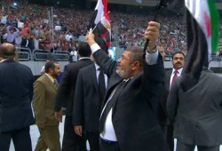 الرئيس مرسي يحيي الحضور رافعًا علمي مصر وسوريا بإستاد القاهرة