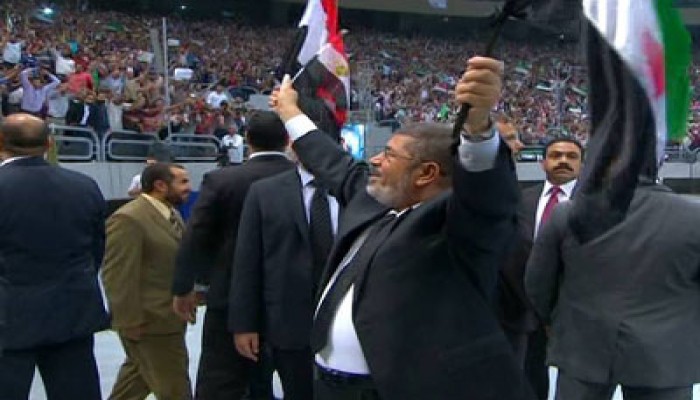 الرئيس مرسي يحيي الحضور رافعًا علمي مصر وسوريا بإستاد القاهرة